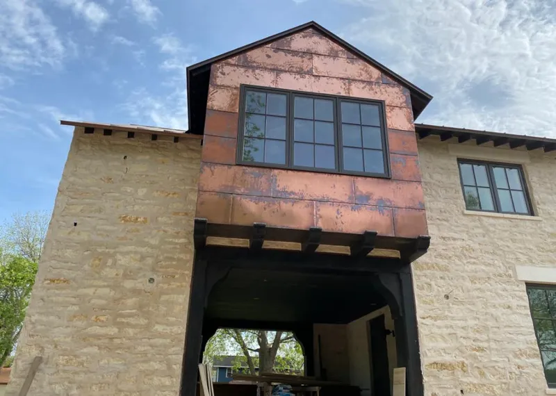 Copper metal panel facade on a stone building for Roof Repair in Otsego